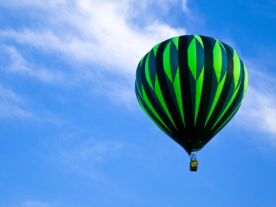 Green Black Striped Hot Air Balloon Flying In Blue Sky