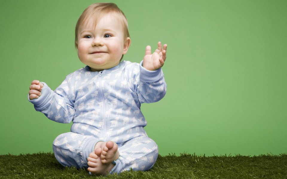 Smiling Cute Baby Sitting On Lawn Studio Portrait