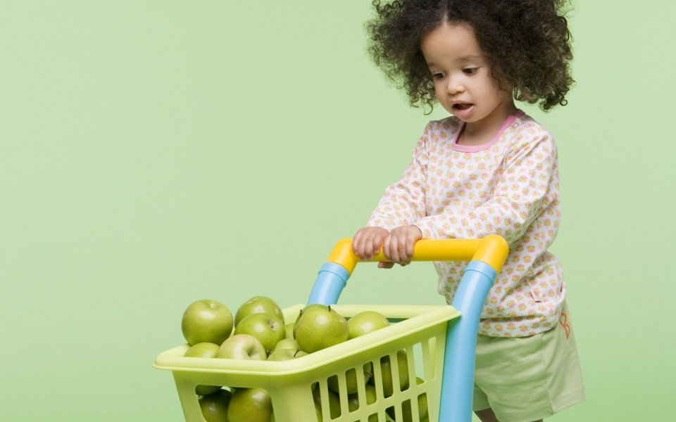 Little Girl Pushing Toy Shopping Cart Full Of Green Apples