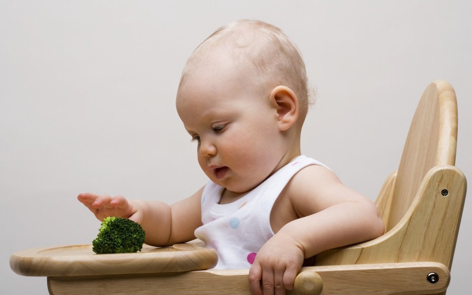 Cute Baby Exploring Broccoli On Wooden High Chair