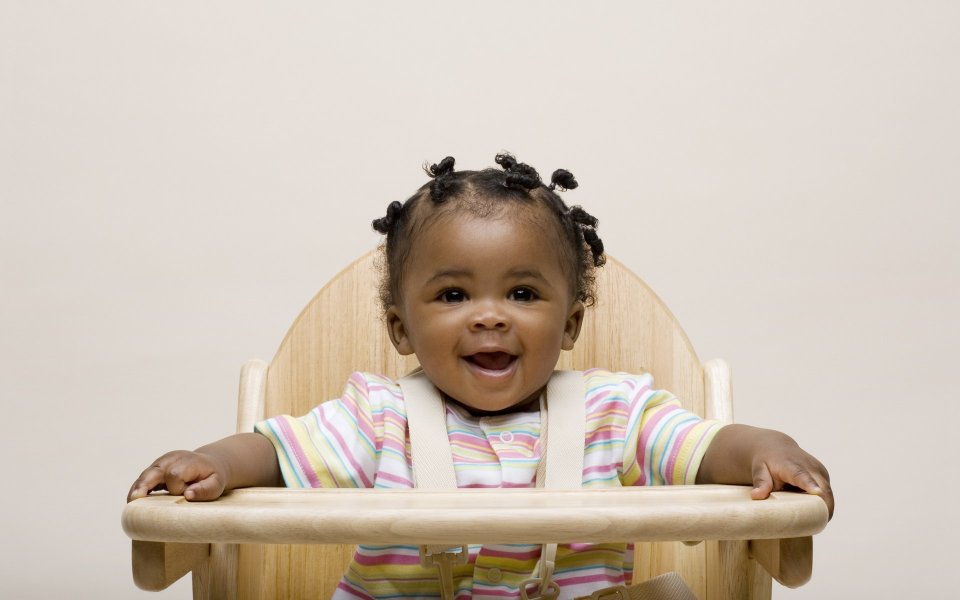 Happy Smiling Black Baby Sitting On Wooden High Chair Portrait
