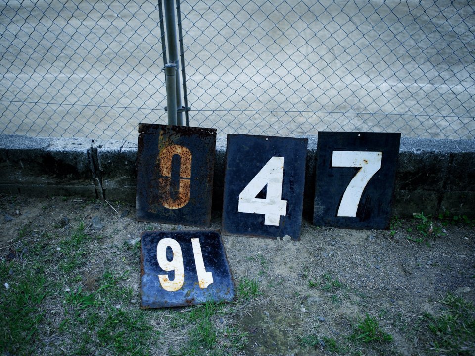 Vintage Rusty Metal Number Signs Near Chain Link Fence