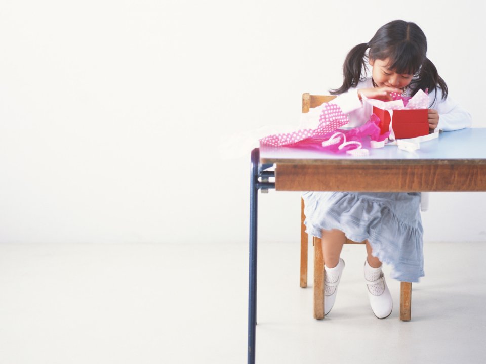 室内开心拆红色礼盒的可爱双马尾小女孩