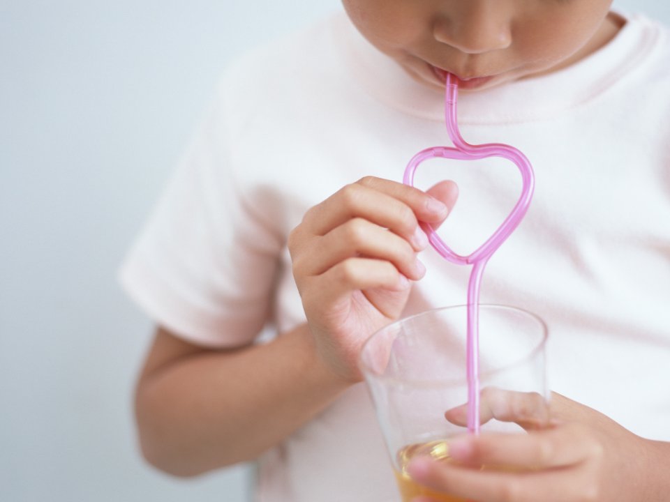 Child Drinking Orange Juice With Pink Heart Shaped Straw