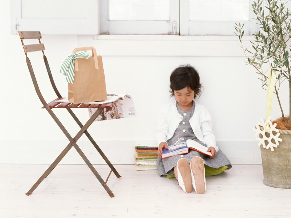Cute Little Girl Reading Books By Bright Home Window