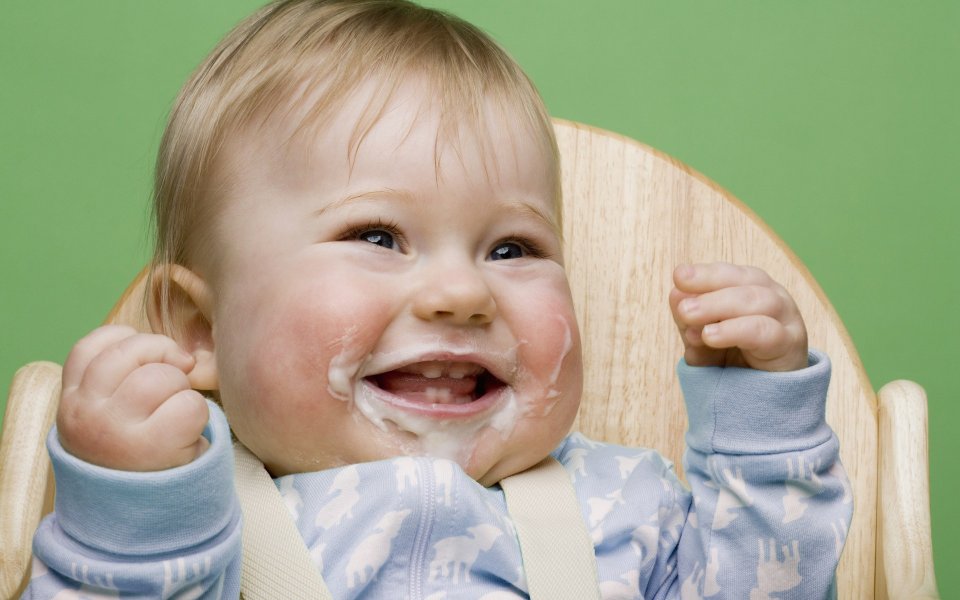 Happy Little Baby With Milk Stains Sitting On Wooden High Chair