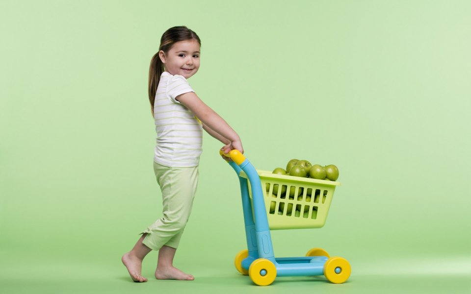 Little Girl Pushing Toy Shopping Cart Full Of Green Apples