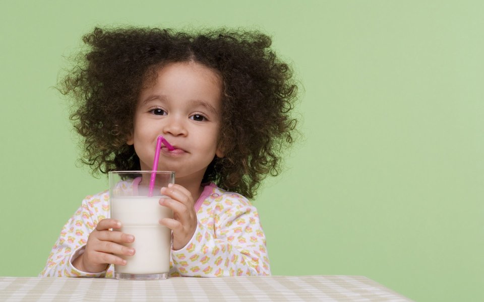 Curly Little Girl Drinking Milk With Pink Straw Portrait