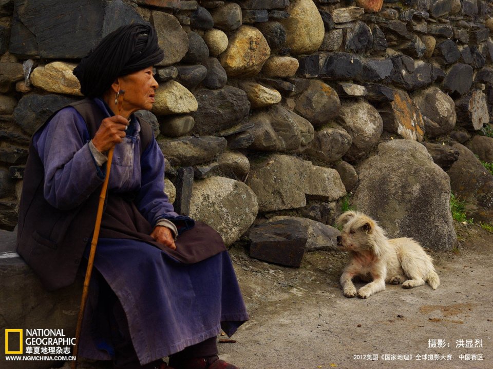 Chinese Rural Elderly Woman With Dog By Stone Wall