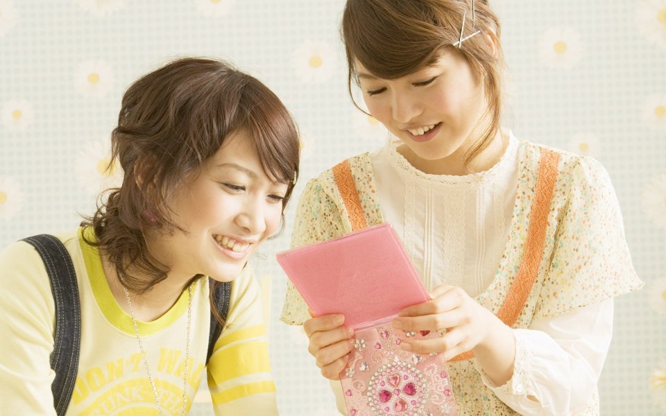 Warm Moment Of Two Japanese Girls Looking At Pink Diary At Home