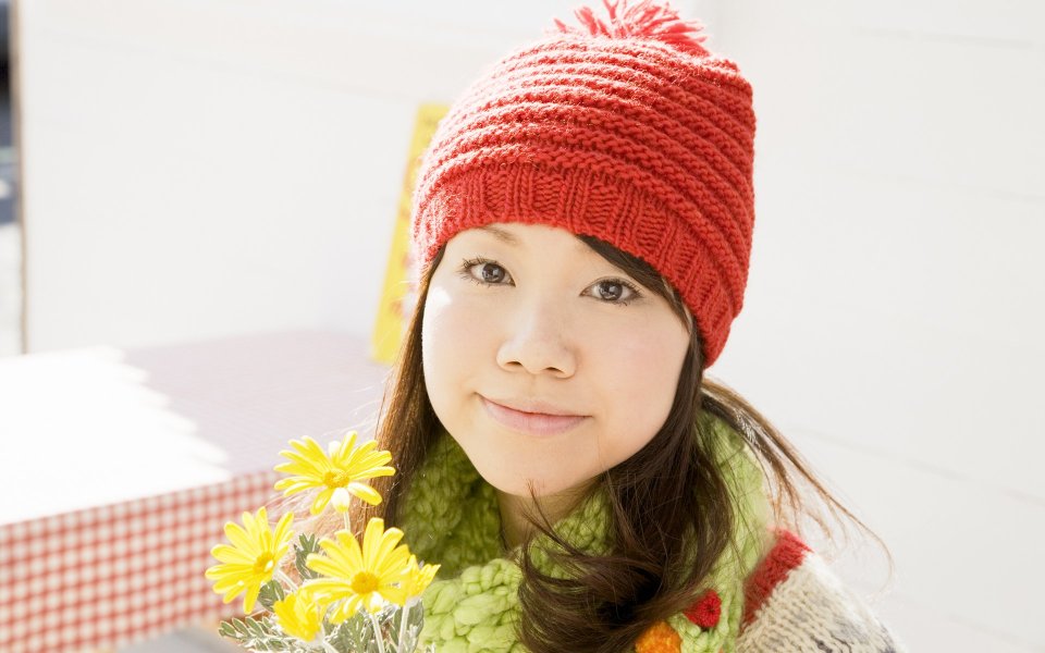 Young Girl In Red Knit Hat Holding Yellow Daisies In Winter Sunshine