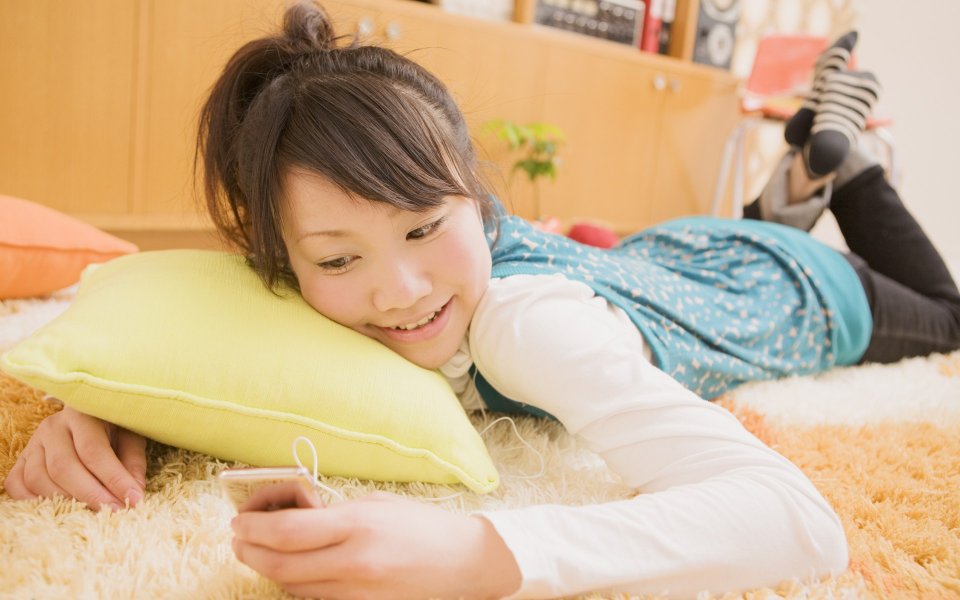 居家少女趴在毛绒地毯上使用智能手机的温馨日常写真