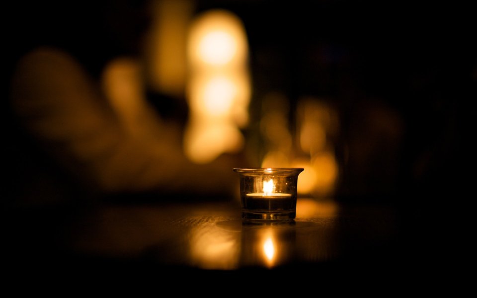 Lit Tea Candle In Glass Holder Dark Table Warm Bokeh Quiet Atmosphere
