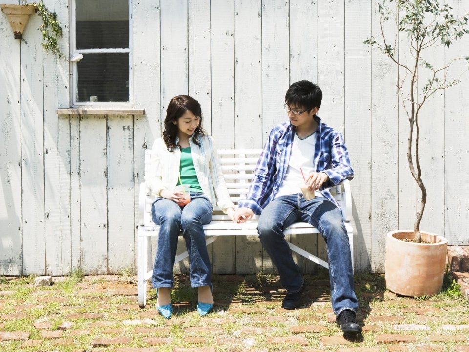 Young Couple Holding Hands On Bench In Summer Courtyard