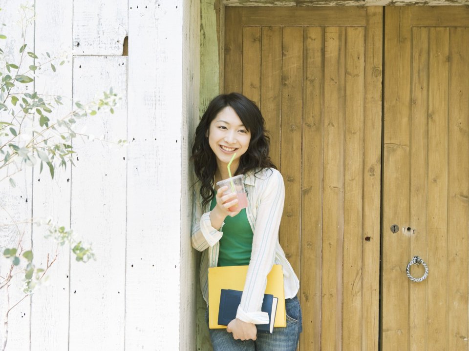 Fresh Japanese Young Woman Leaning On Wooden Door With Drink And Notebooks