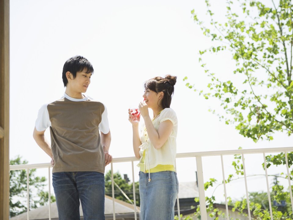 Young Couple Relaxing On Sunny Summer Balcony