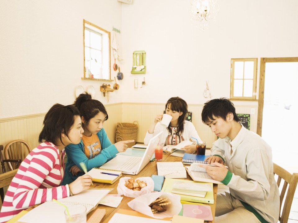 Young Friends Study Discuss Together In Cozy Japanese Cafe