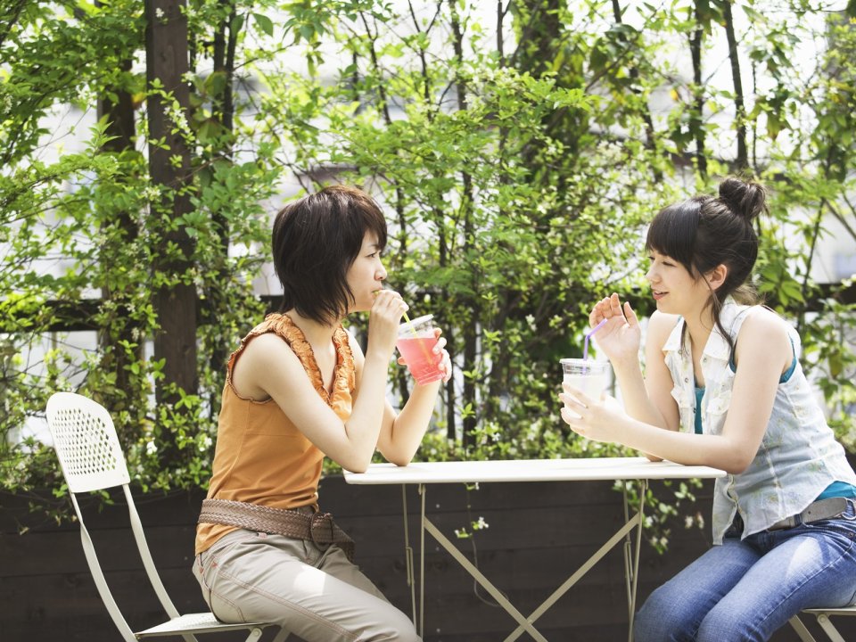 Two Young Girls Drinking Cold Drinks In Spring Garden