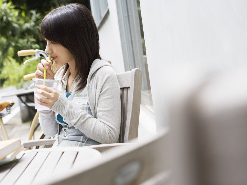 Young Japanese Girl Drinking Iced Drink On Patio Afternoon