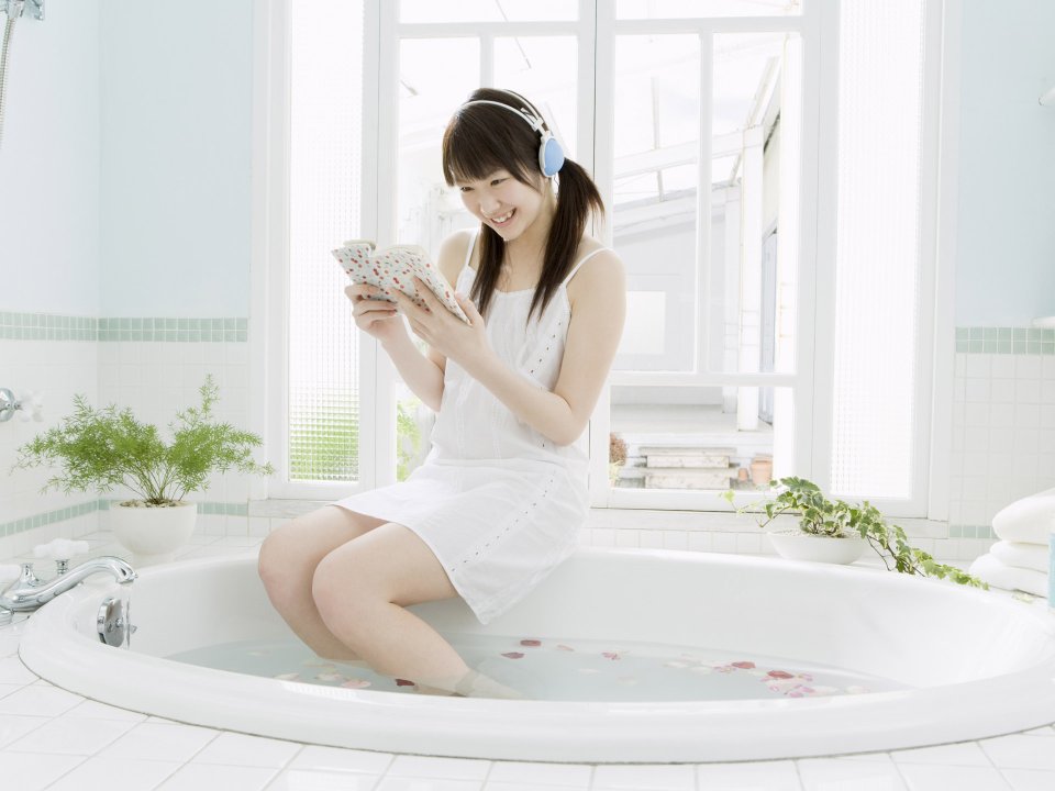 Japanese Young Girl Reading With Headphone In Bright Bathroom