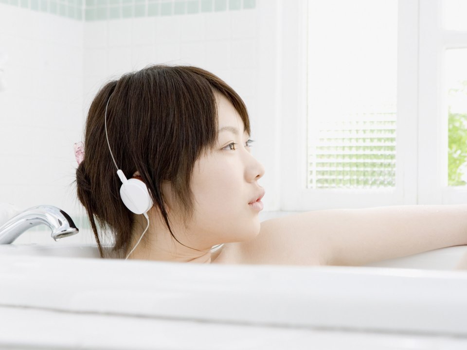 Young Girl Relaxing In Bathtub Listening To Music