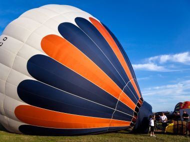 Blue Orange Striped Hot Air Balloon Preparing For Takeoff Under Blue Sky