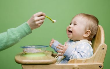 Happy Baby Eating Complementary Food On Wooden High Chair