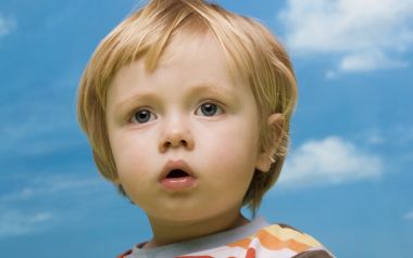 Blonde Blue Eyed Toddler Portrait Against Blue Sky White Clouds