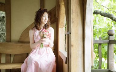 Girl In Pink Dress Holding Bouquet At Wooden Cabin Terrace
