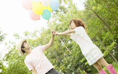 夏日户外林间牵手共握彩色气球的甜蜜情侣