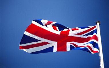 Waving Union Jack Flag Against Blue Sky