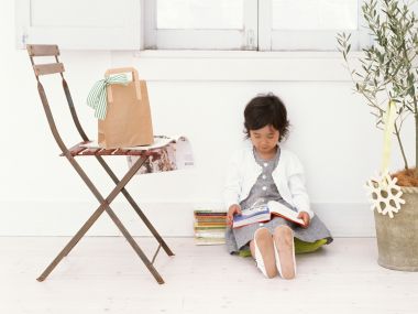 Cute Little Girl Reading Books By Bright Home Window