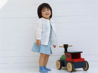 Smiling Little Girl Beside Colorful Wooden Toy Car