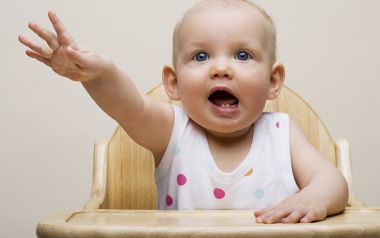 Cute Blue Eyed Baby Reaching Out On Wooden High Chair