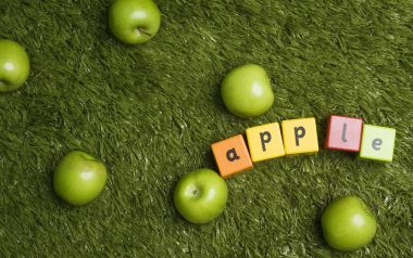 Green Apples And Letter Blocks Spelling Apple On Grass
