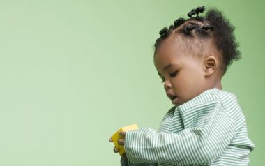淡绿背景下专注玩积木的可爱黑人幼儿写真