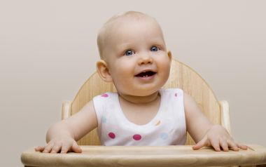 Happy Blue Eyed Baby Sitting On Wooden High Chair