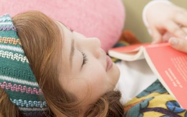 Young Girl Resting At Home Holding Red Book Closeup