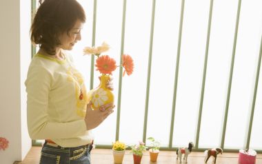 Warm Light Window Young Woman Holding African Daisies At Home