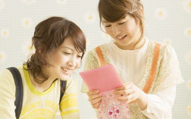 Warm Moment Of Two Japanese Girls Looking At Pink Diary At Home