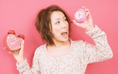 粉色背景下手持两款闹钟的俏皮日系居家少女