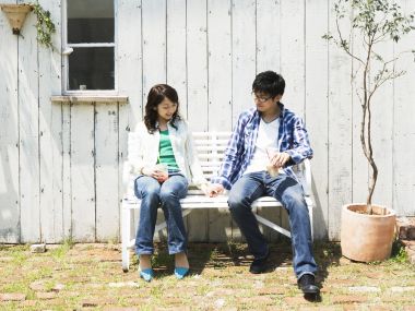 Young Couple Holding Hands On Bench In Summer Courtyard