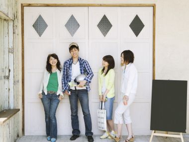 Four Young Friends Casual Group Photo In Front Of White Wood Door