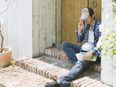 夏日晴天坐在红砖门廊通话的年轻男子