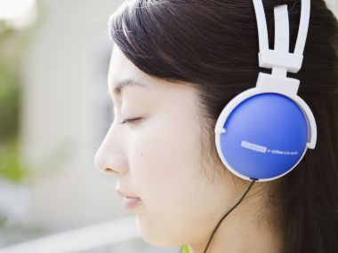 户外闭眼聆听音乐的蓝白头戴耳机少女侧脸人像