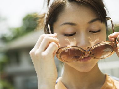 夏日户外手持茶色墨镜的年轻日系女生