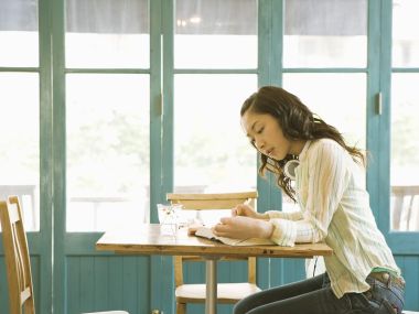 Young Girl Writing Notebook By Cafe Window Sunny Afternoon