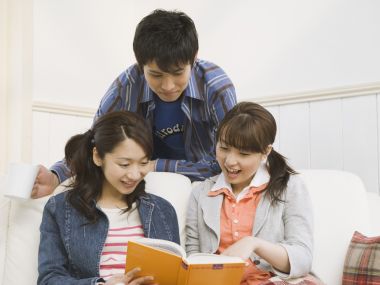 三位年轻友人居家沙发共同阅读的温馨日常