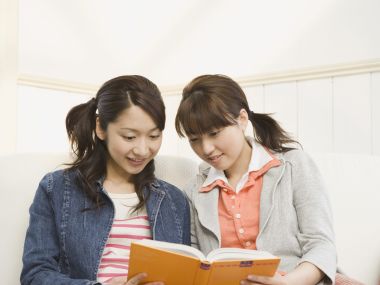 两位年轻闺蜜居家沙发共读休闲读物