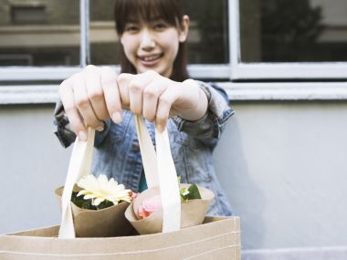 微笑年轻女子递出装有鲜花的牛皮纸手提袋日常写真